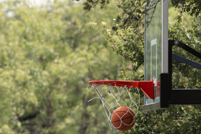 Basketball at the bottom of a net on a backboard goal as a result of a made shot