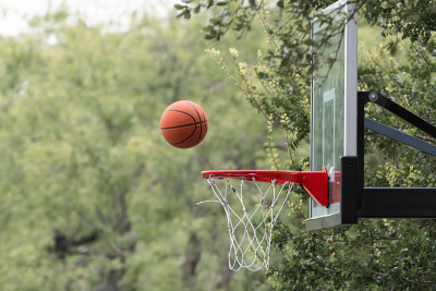 Basketball frozen in mid air as it approaches a goal on a backboard during a shot