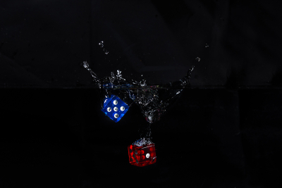 Water droplets and splash from blue and red dice being dropped into water