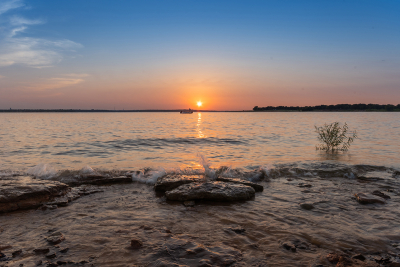 Waves washing over rocks on a lake shore just before sunset
