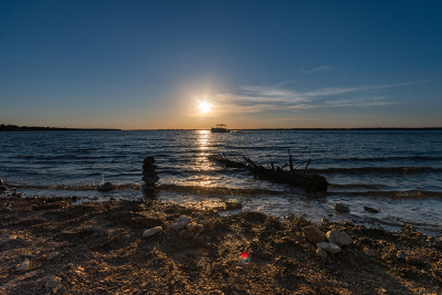 Pontoon boat crossing lake shortly before sunset