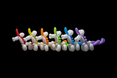 A row of white unicorn balloon animals with a rainbow of colorful manes, tails, and horns on a black background.