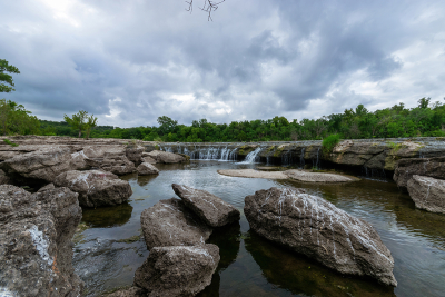Waterfall flowing into pool filled with rocks and boulders